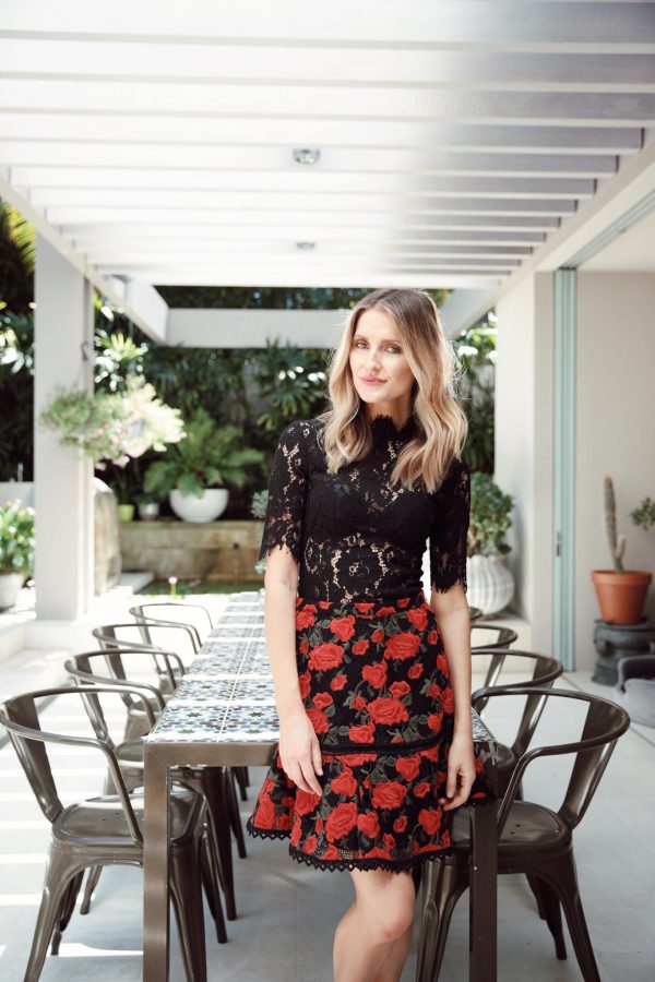 Kate Waterhouse standing outdoors wearing a Rodeo Show Uma lace tee and Rodeo Show Rosette skirt with red rose print
